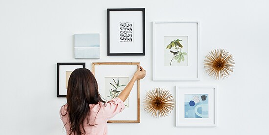 Girl hanging a frame using Command™  Picture Hanging Strips